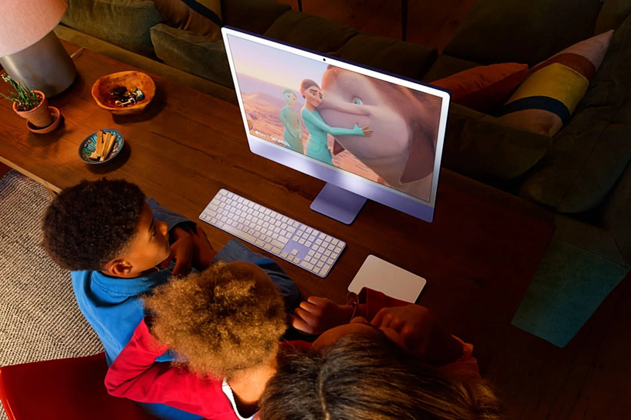 Karşılaştırma: M4 iMac ve M3 iMac - Yenilikler ve İyileştirmeler 16 Retina ekranlı 24 inç M4 iMac, yakınlarda aksesuarları kullanan çocuklar ve ekranda animasyonlu bir film