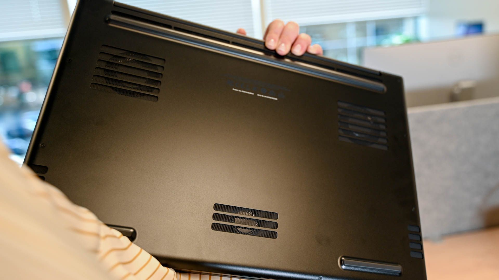 8 Maneras de Acelerar la Carga Lenta ⚡ Descubre cómo cargar tu laptop rápido 9 Una persona sostiene una laptop al revés en sus manos.