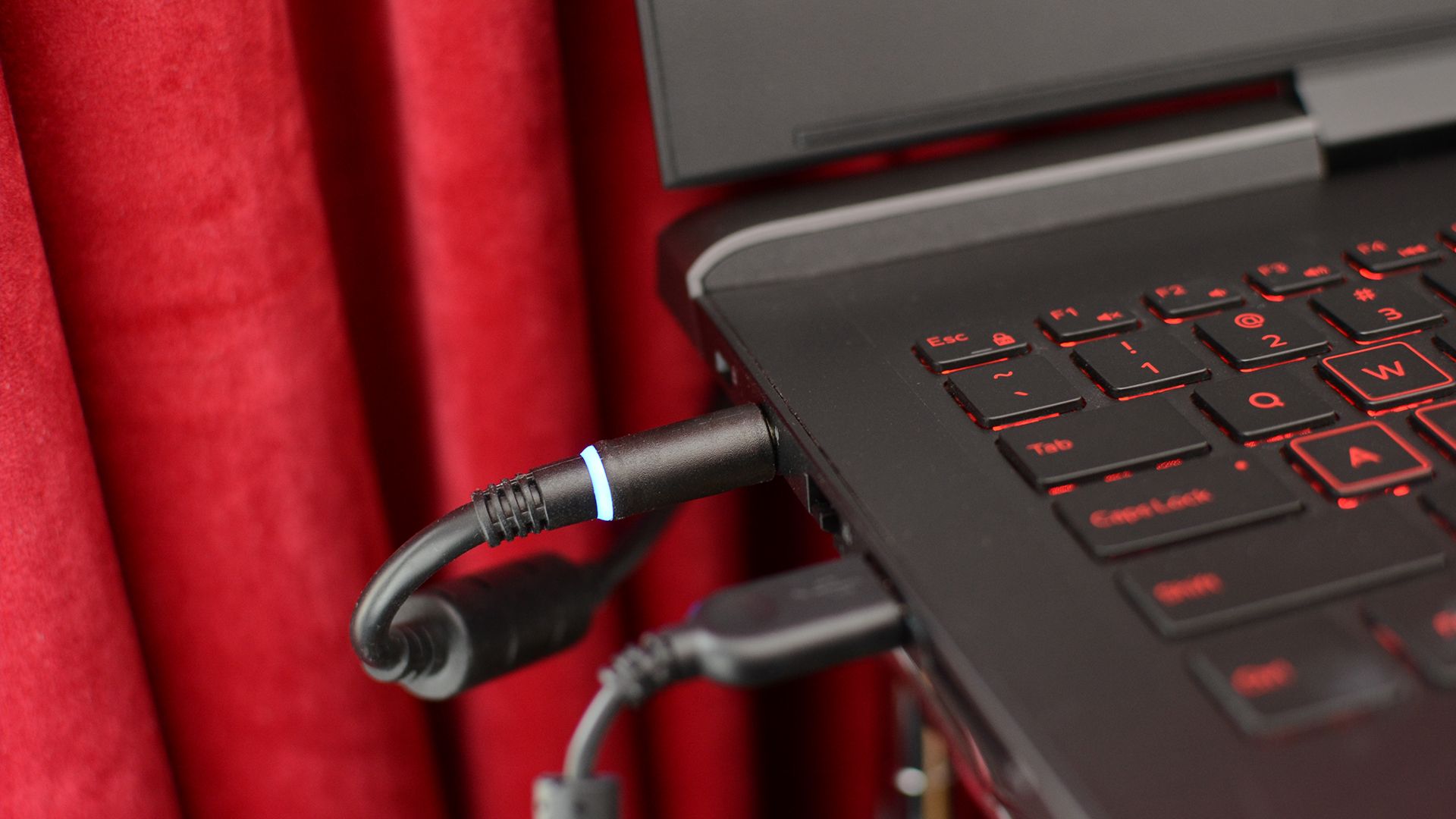 8 Maneras de Acelerar la Carga Lenta ⚡ Descubre cómo cargar tu laptop rápido 7 Un cargador conectado a una laptop cerca de una cortina.