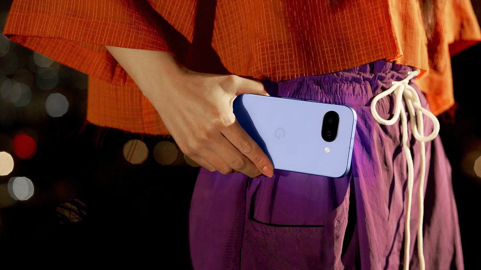Google Pixel 9a vs iPhone 16e: ¡2 premium por menos de $600! 📱💥 103 Primer plano de una mujer sosteniendo un teléfono Google Pixel 9a a la altura de la cintura.