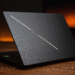 Asus ROG Zephyrus G16 2025 : le roi du jeu et du travail hybrides ? - Texte alternatif : « Asus ROG Zephyrus G16 2025 : un ordinateur portable de jeu noir élégant, partiellement ouvert sur un bureau en bois avec une bande lumineuse diagonale brillante sur le couvercle, conçu pour les jeux hybrides et les performances de travail. »