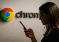 Google Chrome บน Android และความปลอดภัย - ผู้หญิงกำลังใช้โทรศัพท์มือถือ Android หน้าโลโก้ Google Chrome ขนาดใหญ่บนผนัง โดยเน้นถึงความปลอดภัยและการท่องเว็บใน Google Chrome บนอุปกรณ์ Android