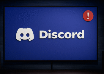 Discord No Route-fout: 6 snelle oplossingen ⚡️ 3 Geen routefout in Discord - Discord-logo op een blauw scherm met een rood uitroepteken als meldingsbadge, wat duidt op een waarschuwing of probleem van de chat-app op een desktopmonitor.