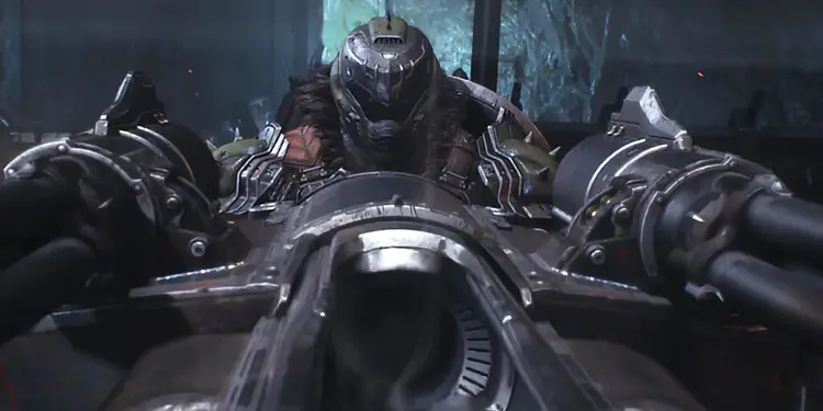 Armas de Doom The Dark Ages: 23 armas reveladas ⚔️🔥 6 Waffen aus Doom The Dark Ages: Der Doom Slayer zielt mit Zwillingskanonen einer Belagerungsmaschine in einer dunklen, höhlenartigen Umgebung.