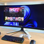Top monitores gaming: monitor ultrawide curvo Alienware en escritorio, con teclado mecánico, auriculares y mando, ideal para setup de juegos en PC.