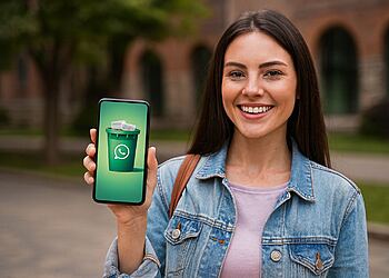 ถังขยะ WhatsApp - หญิงสาวยิ้มแย้มพร้อมไอคอนถังขยะสีเขียวที่มีโลโก้ WhatsApp บนโทรศัพท์มือถือของเธอ แนวคิดถังขยะของ WhatsApp ที่จะทำความสะอาดและเพิ่มพื้นที่ว่างในโทรศัพท์ภายในไม่กี่นาที