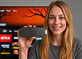 VPN Fire TV – Kvinna som använder Fire TV Stick på TV:n för att titta på Netflix och andra streamingappar med VPN, skyddar sina data och låser upp mer innehåll.