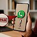 Spam no WhatsApp - Celular com o logotipo do WhatsApp e aviso de spam, ilustrando como ativar o filtro de spam oculto no WhatsApp.