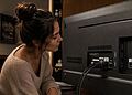 HDMI eARC 与 ARC 对比 - 一位女士正在电视机背面连接线缆，展示了 HDMI ARC 和 eARC 接口，以此说明家庭影院中 HDMI eARC 和 ARC 在音频方面的实际差异。