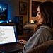 Privacidad en Windows 11 con O&O ShutUp10++ 56 Privacidad en Windows 11 - Mujer usando un portátil en casa configurando opciones de privacidad en Windows 11 con O&O ShutUp10++, mostrando ajustes de seguridad y control de datos en pantalla.