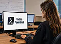 Windows'ta PowerShell Güncellemesi - Bir kadın, bilgisayarından Windows'ta PowerShell'i güncelliyor; ekranda PowerShell logosu ve "PowerShell'i Güncelle" yazısı görünüyor.